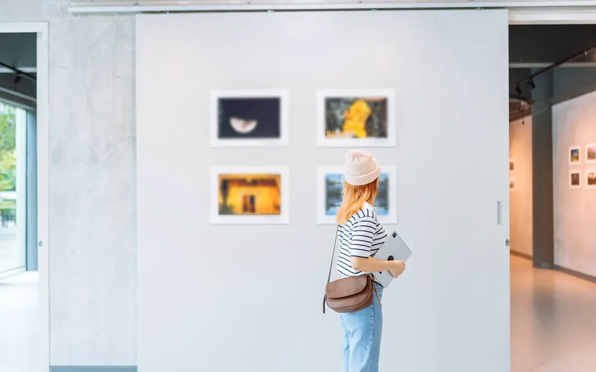 Visitante contemplando obras enmarcadas en una galería de arte