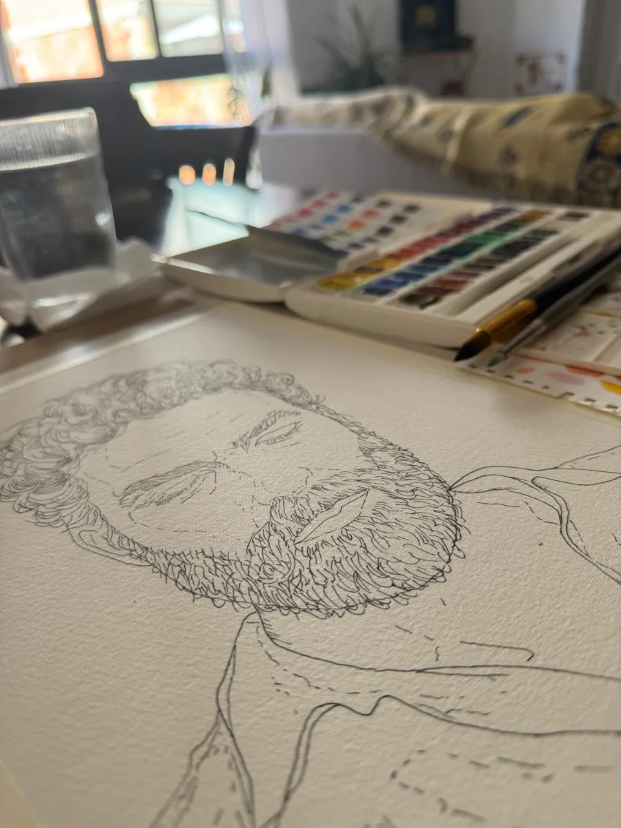 Boceto en tinta del retrato de Jero Romero junto a la paleta de acuarelas, durante el proceso de pintura